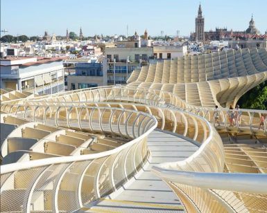 La pasarela curva de madera del Metropol Parasol, también conocida como Entrada a las Setas de Sevilla, ofrece impresionantes vistas del paisaje urbano y la catedral de Sevilla. - ForTwo - Planes para parejas