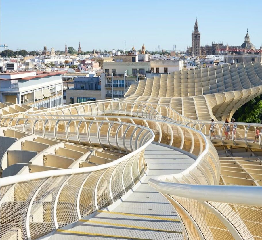 La pasarela curva de madera del Metropol Parasol, también conocida como Entrada a las Setas de Sevilla, ofrece impresionantes vistas del paisaje urbano y la catedral de Sevilla. - ForTwo - Planes para parejas