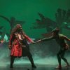 Actores con trajes coloridos dramatizan una escena en el escenario del Teatro Maravillas, rodeados de plantas vibrantes, dando vida a la magia de "Peter Pan, el musical". - ForTwo - Planes para parejas
