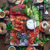 Fotografía cenital de un brunch en el restaurante Brunch en Picnic de Barcelona, con bagels, salmón ahumado, queso crema, alcaparras, tomates, pepinos, café y hierbas en una mesa de madera. - ForTwo - Planes para parejas