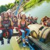 Los visitantes agarran con entusiasmo sus Entradas PortAventura Park mientras disfrutan de un emocionante paseo en montaña rusa sobre aguas brillantes en un glorioso día soleado. - ForTwo - Planes para parejas