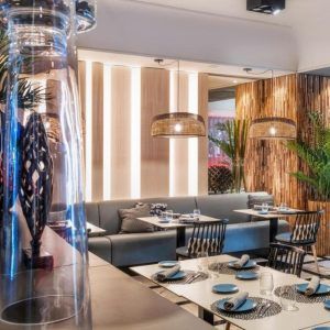 Un elegante y moderno restaurante en el Hotel Sallés Pere IV, con decoración de madera, lámparas colgantes tejidas y elegantes mesas con sillas estampadas, ofrece un menú saludable que complementa perfectamente su ambiente chic como parte del paquete Circuito de Spa + Masaje. - ForTwo - Planes para parejas
