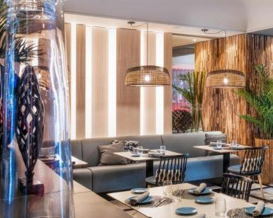 Un elegante y moderno restaurante en el Hotel Sallés Pere IV, con decoración de madera, lámparas colgantes tejidas y elegantes mesas con sillas estampadas, ofrece un menú saludable que complementa perfectamente su ambiente chic como parte del paquete Circuito de Spa + Masaje. - ForTwo - Planes para parejas