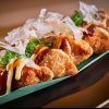 Pruebe los crujientes dumplings fritos del Restaurante asiático Latitude 37 en Palma de Mallorca, adornados con salsa, mayonesa, copos de bonito y cebollas verdes en una hoja de plátano. - ForTwo - Planes para parejas