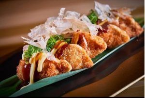 Pruebe los crujientes dumplings fritos del Restaurante asiático Latitude 37 en Palma de Mallorca, adornados con salsa, mayonesa, copos de bonito y cebollas verdes en una hoja de plátano. - ForTwo - Planes para parejas