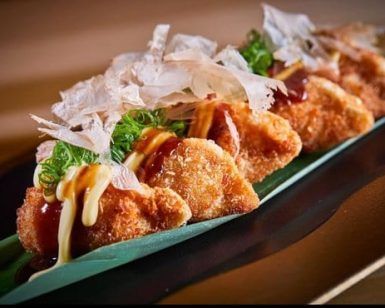 Pruebe los crujientes dumplings fritos del Restaurante asiático Latitude 37 en Palma de Mallorca, adornados con salsa, mayonesa, copos de bonito y cebollas verdes en una hoja de plátano. - ForTwo - Planes para parejas