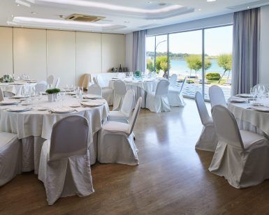 El elegante salón del Restaurante Marea Alta cuenta con mesas redondas con manteles y sillas blancas, ofreciendo un ambiente soleado y al aire libre, como el de Santander. Realce su celebración con el "Menú degustación en el restaurante Marea Alta (Santander)". - ForTwo - Planes para parejas