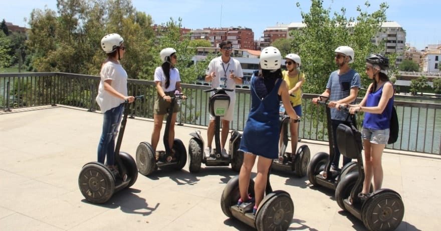 Un grupo con cascos, reunidos en círculo sobre Segways, comienza la soleada Ruta en Segway por Sevilla. - ForTwo - Planes para parejas
