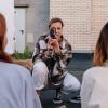 De rodillas y con una camisa a cuadros, alguien apunta juguetonamente con una cámara vintage a una pareja de espaldas durante una "Ruta fotográfica en pareja por The Set Lab (Madrid). - ForTwo - Planes para parejas
