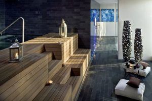 Descubra la tranquilidad de un spa moderno en Serena Spa, Meliá Barcelona Sky. Disfrute de escaleras de madera, faroles, velas, cojines y jarrones altos junto a una mesa pequeña, ideales para relajarse o disfrutar de una experiencia rejuvenecedora con el Desayuno Buffet y el Circuito Spa y Masaje en pareja. - ForTwo - Planes para parejas