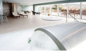 Relájese en el moderno spa con solárium del Barceló Granada Congress, donde las tumbonas junto a una fuente de agua le brindan tranquilidad. Disfrute del ambiente sereno y de las vistas de la ciudad a través de los amplios ventanales en días despejados. - ForTwo - Planes para parejas