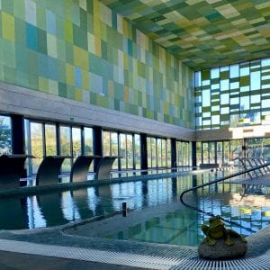 Ubicada en Zaragoza, la piscina cubierta del Club Ranillas presume de coloridas paredes de azulejos y amplios ventanales. Una pintoresca estatua de rana junto al agua realza la atmósfera serena de este oasis de spa, Día en el spa del Club Ranillas. - ForTwo - Planes para parejas