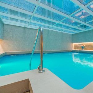 Una tranquila piscina cubierta de agua turquesa, bajo un techo de cristal y una iluminación suave, crea un ambiente de spa sereno en el Circuito de Spa & Masaje del Hotel Sallés Pere IV, Barcelona. - ForTwo - Planes para parejas