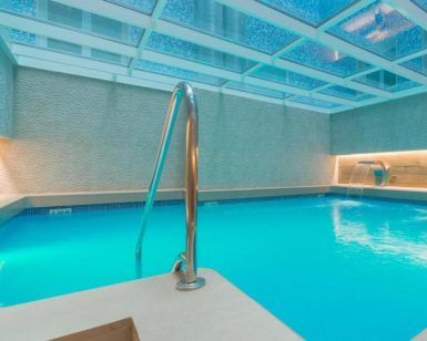 Una tranquila piscina cubierta de agua turquesa, bajo un techo de cristal y una iluminación suave, crea un ambiente de spa sereno en el Circuito de Spa & Masaje del Hotel Sallés Pere IV, Barcelona. - ForTwo - Planes para parejas