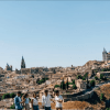 Cinco personas paseando disfrutan de una impresionante vista de los edificios históricos de Madrid bajo un cielo azul claro, que recuerda a escenas de "Madrid y Toledo: Excursión guiada de un día y Museo del Prado". - ForTwo - Planes para parejas