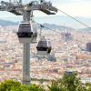 Disfrute de impresionantes vistas mientras los teleféricos sobrevuelan el paisaje urbano de Barcelona con montañas lejanas y cielos parcialmente nublados como telón de fondo. Reserve sus Entradas Teleférico de Barcelona para una aventura inigualable sobre la vibrante ciudad. - ForTwo - Planes para parejas