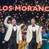 Los artistas en el escenario bajo el cartel "Todo por la Matria - Los Morancos (Madrid)", vestidos con trajes formales y rodeados de cascadas de confeti, capturan el espíritu vibrante de Madrid. - ForTwo - Planes para parejas
