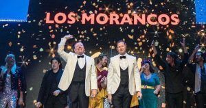 Los artistas en el escenario bajo el cartel "Todo por la Matria - Los Morancos (Madrid)", vestidos con trajes formales y rodeados de cascadas de confeti, capturan el espíritu vibrante de Madrid. - ForTwo - Planes para parejas