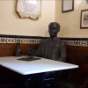 Entre azulejos decorativos y cuadros enmarcados, una estatua de bronce reposa elegantemente en una mesa de café. Ideal para reflexionar durante "Federico García Lorca: Tour guiado por Granada", que captura la esencia artística de Lorca. - ForTwo - Planes para parejas