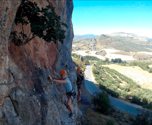 Dos aventureros recorren la Vía Ferrata de Moclín con el impresionante paisaje de Granada como telón de fondo. A continuación, una carretera panorámica resalta su emocionante viaje en medio del esplendor de la naturaleza utilizando Entradas para Vía Ferrata de Moclín: Visita guiada desde Granada. - ForTwo - Planes para parejas