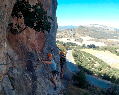 Dos aventureros recorren la Vía Ferrata de Moclín con el impresionante paisaje de Granada como telón de fondo. A continuación, una carretera panorámica resalta su emocionante viaje en medio del esplendor de la naturaleza utilizando Entradas para Vía Ferrata de Moclín: Visita guiada desde Granada. - ForTwo - Planes para parejas