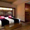 El Hotel Vincci Soho de Madrid ofrece una moderna habitación con dos camas, detalles en rojo y negro, cabecero floral, suelo de madera y baño con puerta abierta. Ubicado en el vibrante corazón de la ciudad, combina un diseño elegante con un ambiente cálido para una experiencia acogedora. - ForTwo - Planes para parejas