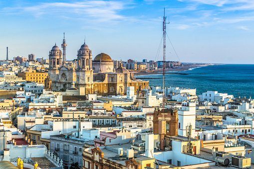 Disfrute del pintoresco paisaje urbano de Cádiz, con su Catedral, sus edificios blancos y su costa bajo un cielo azul. Explore su rica historia con la "Visita guiada por la historia de Cádiz" para vivir una experiencia inolvidable. - ForTwo - Planes para parejas