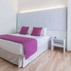 Disfrute de una habitación moderna con cama doble, ropa de cama blanca y morada, cabecero alto y mesita de noche en Escapada en la Costa Blanca del hotel Albahia (Alicante). Disfrute del encanto de Alicante cerca de las resplandecientes costas de la Costa Blanca. - ForTwo - Planes para parejas
