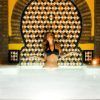 Una mujer en bikini se encuentra en la piscina cubierta de azulejos del Aljibe de San Miguel Granada, iluminada por una luz ambiental y una pared decorativa, capturando el lujo de la experiencia del Tratamiento Harem con masaje con crema floral. - ForTwo - Planes para parejas