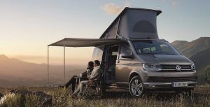Gente disfrutando de una puesta de sol cerca de Barcelona con una VanvanCamper con techo elevable y toldo, con un pintoresco telón de fondo de montaña. - ForTwo - Planes para parejas
