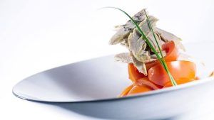 Disfrute de una comida gourmet con rodajas de zanahoria naranja y tierna ave, elegantemente presentada en el Restaurante Ampar en el Palau de la Mar de Valencia. - ForTwo - Planes para parejas