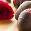 Fresas cubiertas de chocolate y una rosa roja dispuestas artísticamente evocan el estilo romántico del Taller de aperitivos afrodisíacos de Barcelona. - ForTwo - Planes para parejas