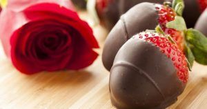 Fresas cubiertas de chocolate y una rosa roja dispuestas artísticamente evocan el estilo romántico del Taller de aperitivos afrodisíacos de Barcelona. - ForTwo - Planes para parejas