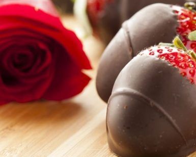 Fresas cubiertas de chocolate y una rosa roja dispuestas artísticamente evocan el estilo romántico del Taller de aperitivos afrodisíacos de Barcelona. - ForTwo - Planes para parejas