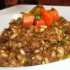 En el Restaurante Galipán (Valencia), disfrute de un lujoso risotto con tiernos trozos de carne, vibrantes zanahorias cortadas en cubitos y frescas hierbas verdes, servido artísticamente en un tazón blanco. - ForTwo - Planes para parejas