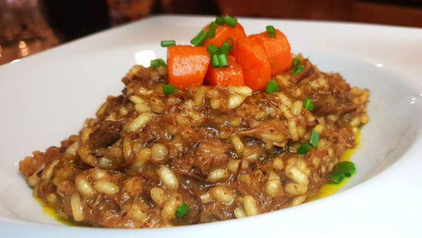 En el Restaurante Galipán (Valencia), disfrute de un lujoso risotto con tiernos trozos de carne, vibrantes zanahorias cortadas en cubitos y frescas hierbas verdes, servido artísticamente en un tazón blanco. - ForTwo - Planes para parejas