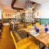 El restaurante Bache San Pedro (Sevilla) cuenta con acogedoras mesas de madera, cristalería azul vibrante, sillas amarillas y azulejos de pared decorativos que encarnan el encanto de Sevilla. - ForTwo - Planes para parejas