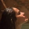 Bajo la suave luz de un espacio poco iluminado, una persona con el cabello mojado disfruta del agua relajante de la ducha, que recuerda a un baño turco en Córdoba: baño árabe con masaje MIMMA. - ForTwo - Planes para parejas