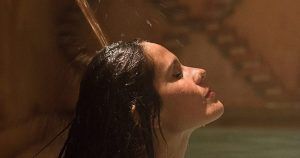 Bajo la suave luz de un espacio poco iluminado, una persona con el cabello mojado disfruta del agua relajante de la ducha, que recuerda a un baño turco en Córdoba: baño árabe con masaje MIMMA. - ForTwo - Planes para parejas