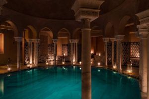 La piscina cubierta elegantemente tenue en Hammam Al Ándalus Málaga, rodeada de arcos y azulejos intrincados, presenta la experiencia exclusiva "Exclusivo MIDRA en Hammam Al Ándalus Málaga". - ForTwo - Planes para parejas