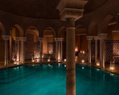 La piscina cubierta elegantemente tenue en Hammam Al Ándalus Málaga, rodeada de arcos y azulejos intrincados, presenta la experiencia exclusiva "Exclusivo MIDRA en Hammam Al Ándalus Málaga". - ForTwo - Planes para parejas