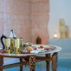 Una bandeja con tetera, tazas y pasteles junto a la piscina, bañada por la luz de las velas, evoca la serena elegancia del “Hammam nocturno en los baños árabes de Al-Haram (Granada)” en una estancia bellamente decorada. - ForTwo - Planes para parejas