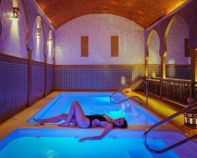 Relajarse junto a una piscina cubierta iluminada con techo abovedado y azulejos decorativos se siente como entrar en el Baño árabe para dos con masaje completo en Medina Aljarafe (Sevilla), que ofrece una escapada serena. - ForTwo - Planes para parejas