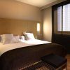 Experimente la comodidad en el Hotel Barceló (Valencia) con una moderna habitación que cuenta con una acogedora cama doble, un elegante cabecero de madera y un gran ventanal con elegantes cortinas negras. - ForTwo - Planes para parejas