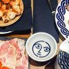 Una mesa con platos variados como pasta, pan y salsa de la Pulpería Can Lampazas Para-lel (Barcelona) con platos adornados con patrones azules. - ForTwo - Planes para parejas
