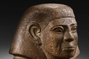 Un antiguo busto de piedra con tocado y expresión solemne, sobre un fondo oscuro, se puede ver con una Entrada al Museo Egipto (Barcelona). - ForTwo - Planes para parejas