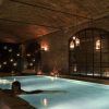 En una zona de piscina subterránea poco iluminada, con paredes de ladrillo y luces colgantes, que recuerda a la "Experiencia Baño termal con masaje en Aires de Barcelona", experimente momentos serenos de relajación. - ForTwo - Planes para parejas