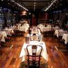 Experimente un elegante ambiente de restaurante con pisos de madera, manteles blancos y luces de cadena mientras disfruta de impresionantes vistas al mar de los barcos deslizándose con el "Paseo por el Sena en barco con cena de lujo (París)" para una velada perfecta. - ForTwo - Planes para parejas