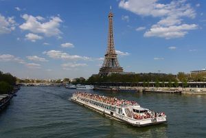 La Vuelta en barco por el río Sena (París) ofrece impresionantes vistas de la ciudad, pasando sin esfuerzo junto a la Torre Eiffel bajo un cielo adornado con nubes dispersas. - ForTwo - Planes para parejas