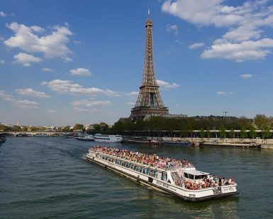La Vuelta en barco por el río Sena (París) ofrece impresionantes vistas de la ciudad, pasando sin esfuerzo junto a la Torre Eiffel bajo un cielo adornado con nubes dispersas. - ForTwo - Planes para parejas
